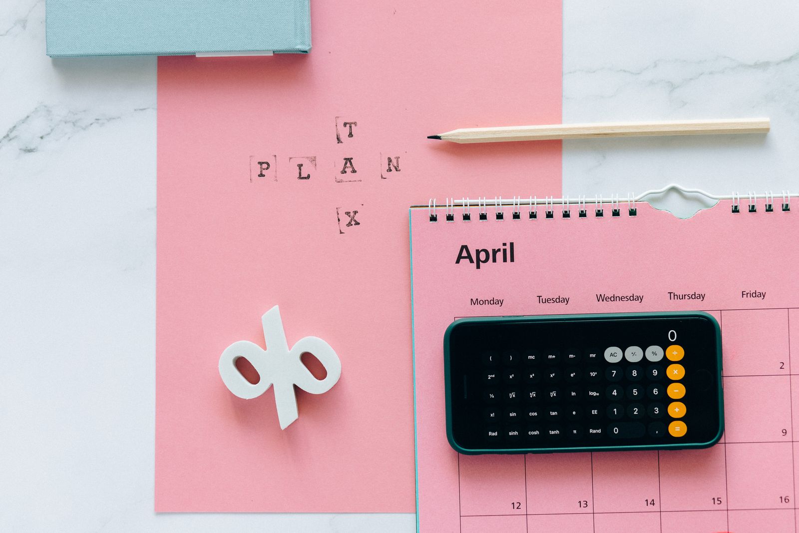 A flat lay of a tax plan note, a percentage symbol, a calculator and a calendar
